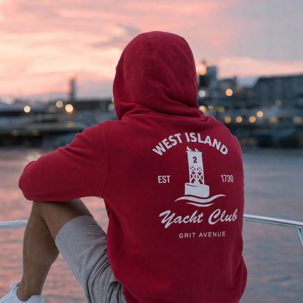 Person wearing a red hoodie with 'West Island Yacht Club' logo on a boat at sunset.